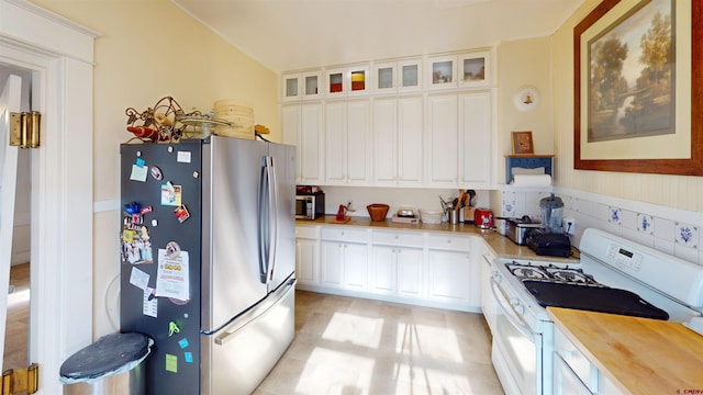 kitchen featuring white cabinetry, stainless steel refrigerator, and white range with gas cooktop