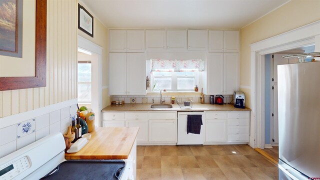 kitchen with stainless steel refrigerator, white cabinetry, dishwasher, sink, and plenty of natural light