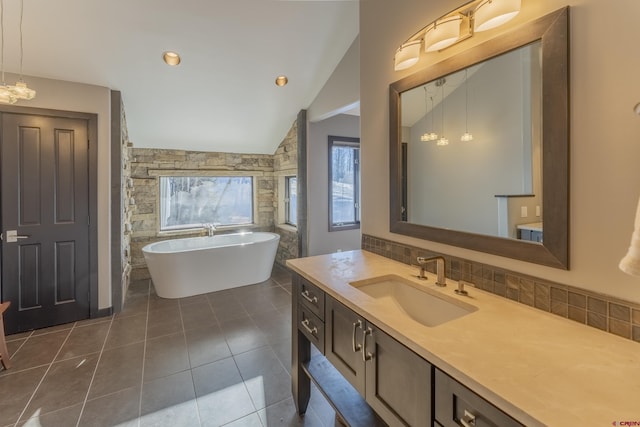 bathroom with vanity, lofted ceiling, a bath, tile patterned flooring, and decorative backsplash