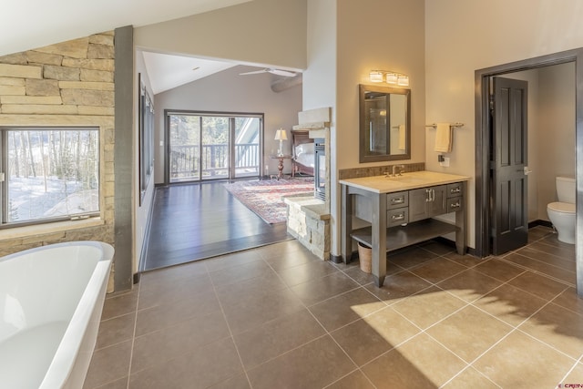 bathroom featuring vanity, vaulted ceiling, tile patterned flooring, toilet, and a tub