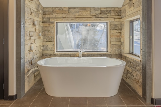 bathroom with tile patterned floors, a wealth of natural light, and a tub