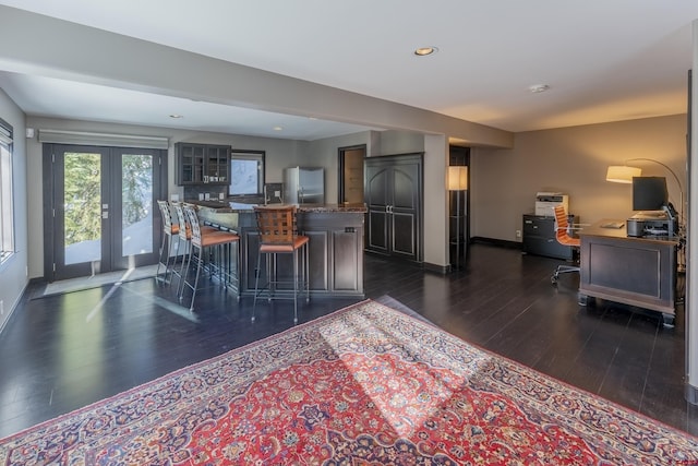 kitchen featuring a kitchen breakfast bar, stainless steel fridge, a center island, and dark wood-type flooring