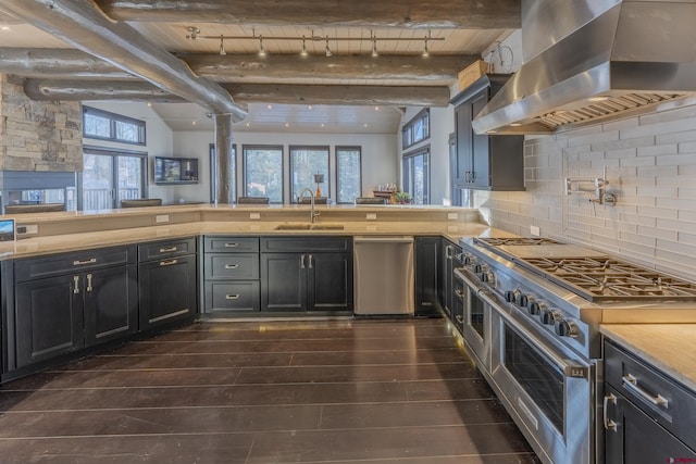 kitchen featuring decorative backsplash, wall chimney exhaust hood, stainless steel appliances, sink, and beam ceiling