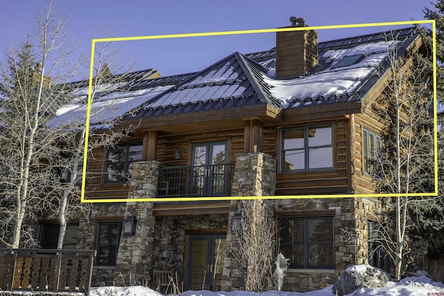 view of snow covered exterior with french doors and a balcony