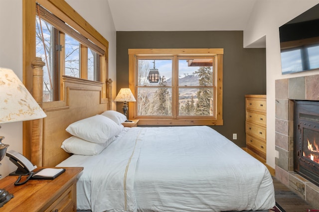 bedroom featuring lofted ceiling and a tile fireplace