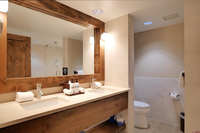 bathroom featuring vanity, tile walls, and toilet