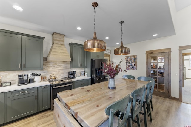 kitchen featuring pendant lighting, custom exhaust hood, light hardwood / wood-style flooring, decorative backsplash, and stainless steel appliances