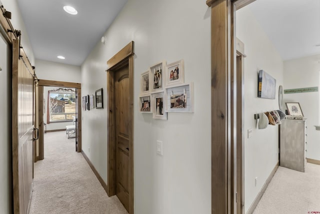 hall featuring a barn door and light colored carpet