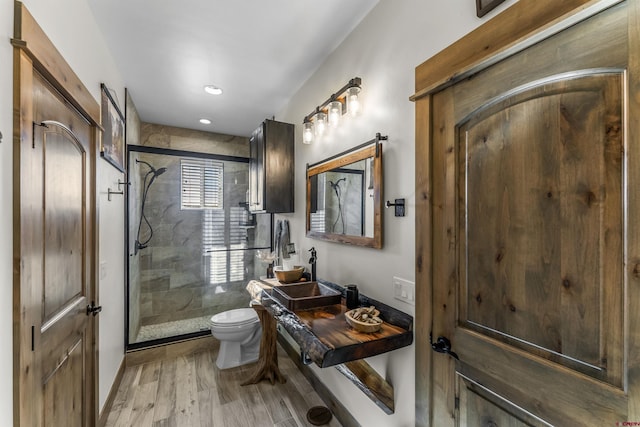 bathroom with hardwood / wood-style flooring, toilet, and an enclosed shower