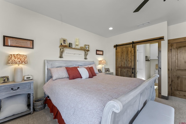 carpeted bedroom with a barn door and ceiling fan