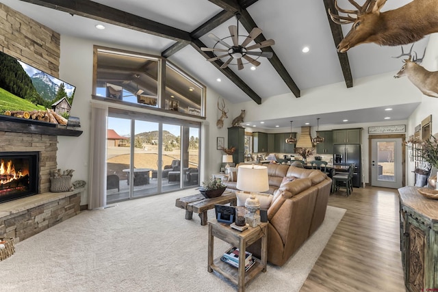 living room featuring ceiling fan, beam ceiling, high vaulted ceiling, a fireplace, and light hardwood / wood-style floors