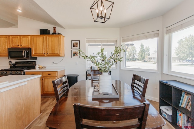 dining space featuring a chandelier, light hardwood / wood-style floors, and vaulted ceiling