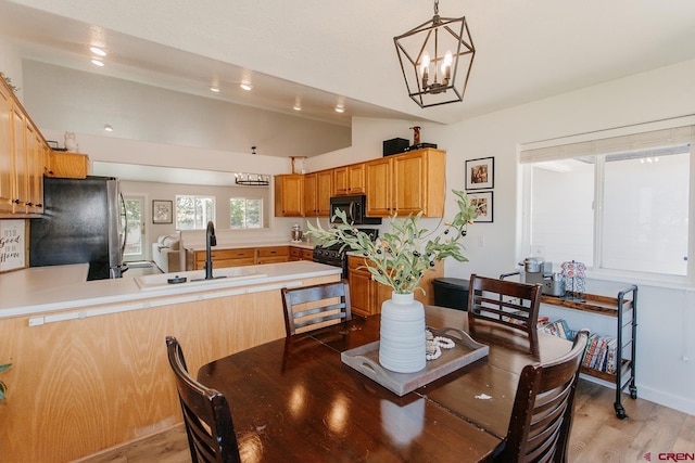 dining space with hardwood / wood-style flooring, a notable chandelier, and sink