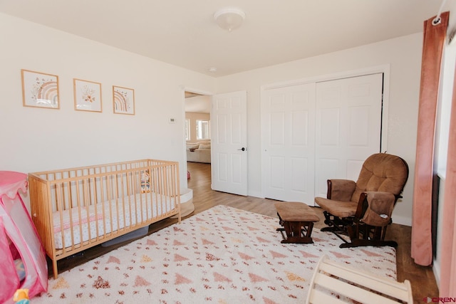 bedroom featuring hardwood / wood-style floors, a crib, and a closet