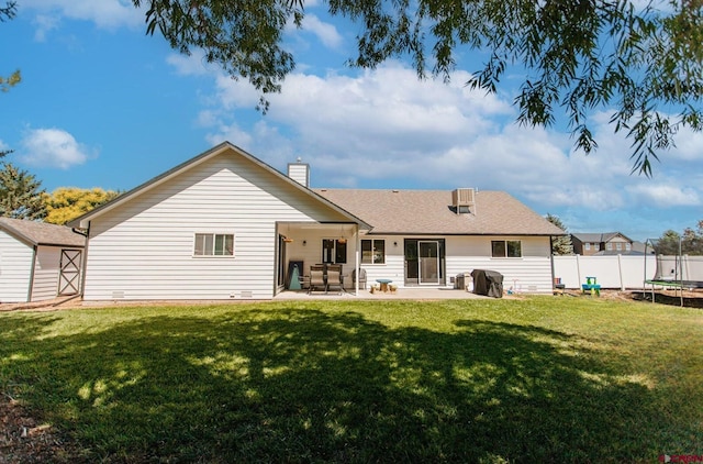 rear view of house featuring a lawn, a patio area, and a trampoline