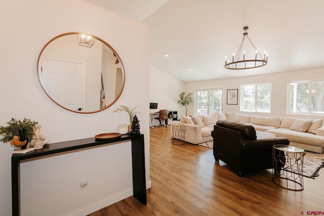 living room with wood-type flooring, vaulted ceiling, and a notable chandelier