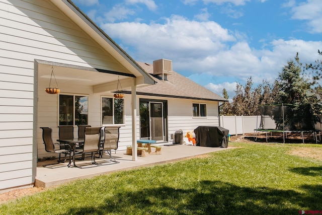 rear view of property with a lawn, a patio area, and a trampoline