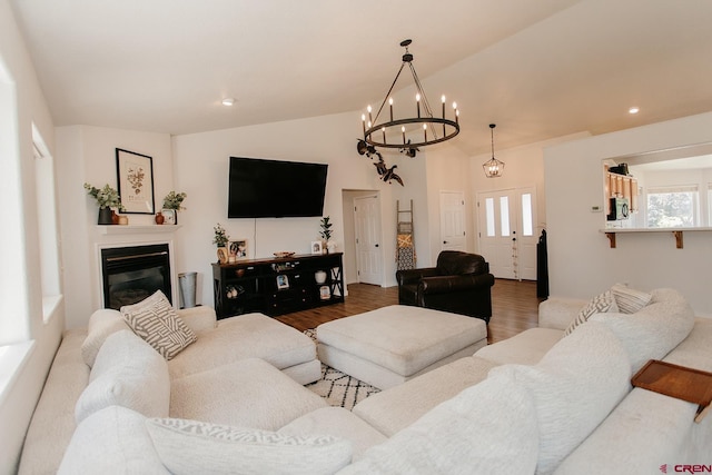 living room with a chandelier, wood-type flooring, and lofted ceiling