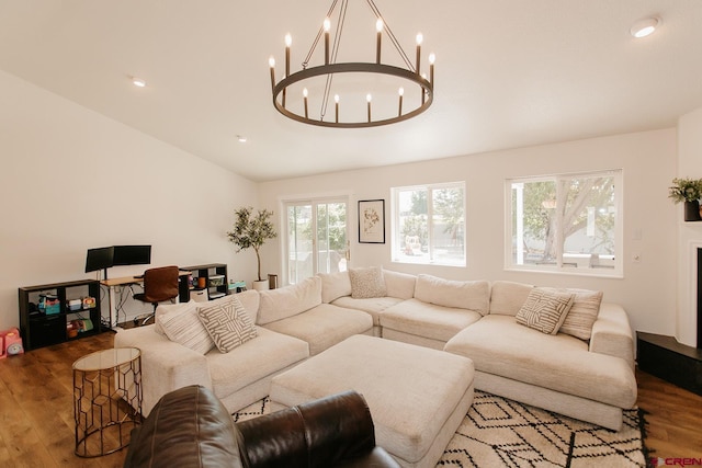 living room with a notable chandelier, wood-type flooring, and vaulted ceiling