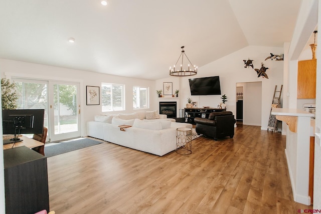 living room featuring light hardwood / wood-style floors, lofted ceiling, and an inviting chandelier