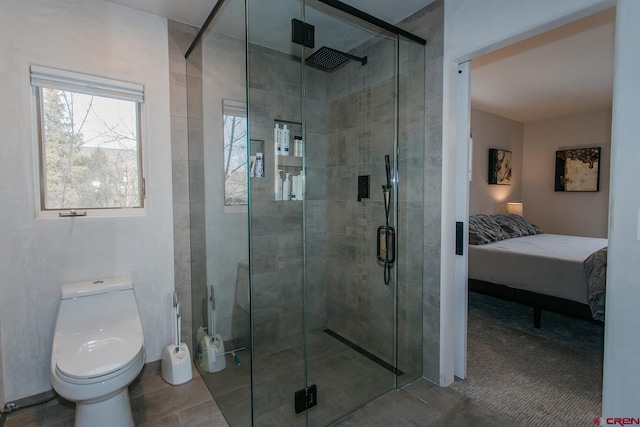 bathroom featuring a shower with door and toilet