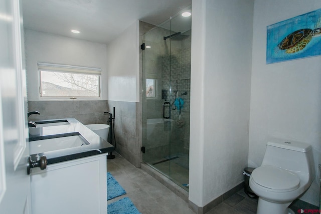 bathroom with vanity, toilet, a shower with door, and tile walls