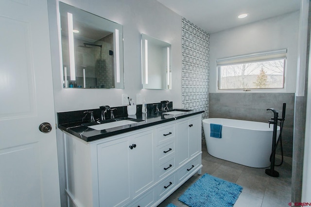 bathroom featuring tile patterned flooring, vanity, a tub to relax in, and tile walls