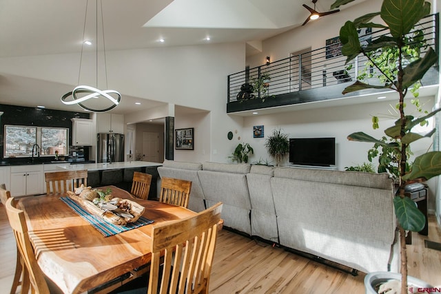 dining space featuring light hardwood / wood-style floors, sink, and high vaulted ceiling