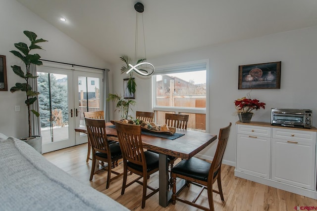 dining area with a wealth of natural light, french doors, lofted ceiling, and light wood-type flooring