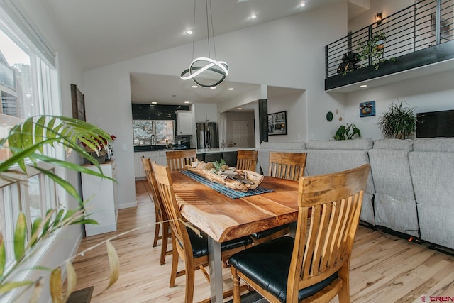 dining room with light hardwood / wood-style floors, high vaulted ceiling, and sink