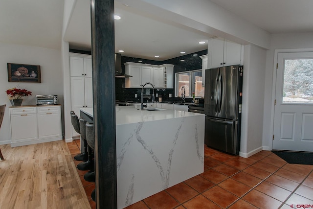 kitchen featuring white cabinets, decorative backsplash, sink, and stainless steel refrigerator