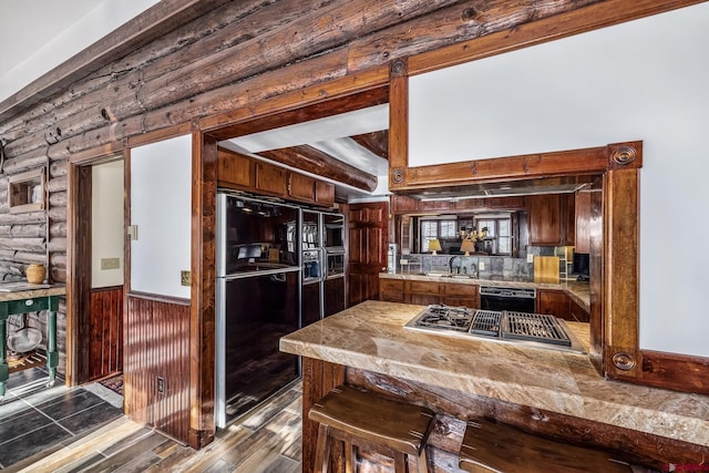 kitchen featuring stainless steel gas stovetop, kitchen peninsula, sink, and fridge