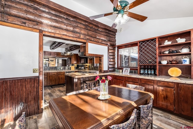 dining room featuring vaulted ceiling with beams, light hardwood / wood-style flooring, and rustic walls