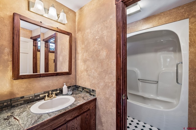 bathroom with backsplash, a shower, and vanity