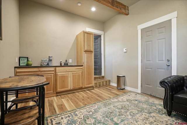 bar featuring light hardwood / wood-style floors, sink, and beam ceiling