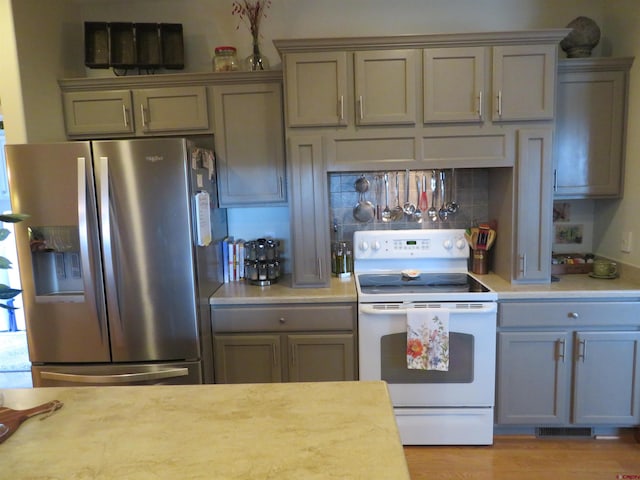 kitchen featuring decorative backsplash, stainless steel fridge with ice dispenser, light wood-type flooring, and white electric range