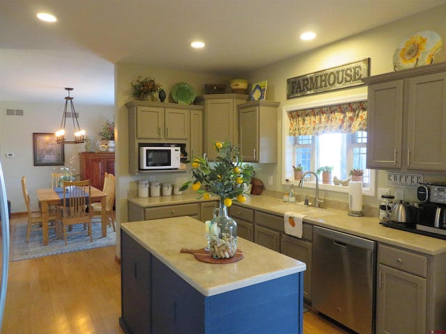 kitchen featuring dishwasher, sink, hanging light fixtures, light hardwood / wood-style floors, and a kitchen island