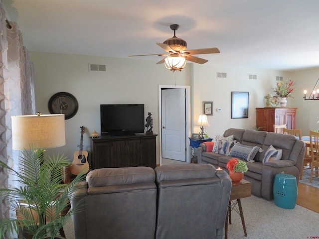 living room featuring ceiling fan with notable chandelier