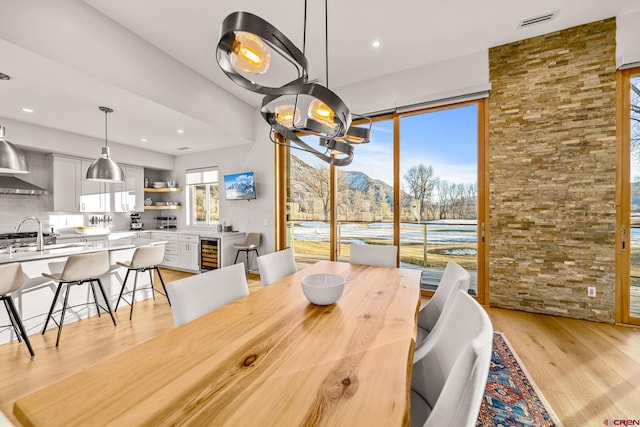 dining space featuring light wood-type flooring, sink, and wine cooler