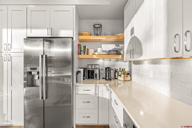 kitchen featuring decorative backsplash, stainless steel fridge, and white cabinetry