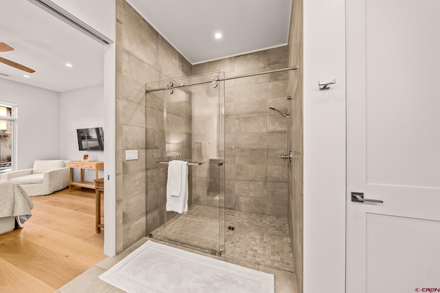 bathroom with hardwood / wood-style flooring, ceiling fan, and a shower with shower door