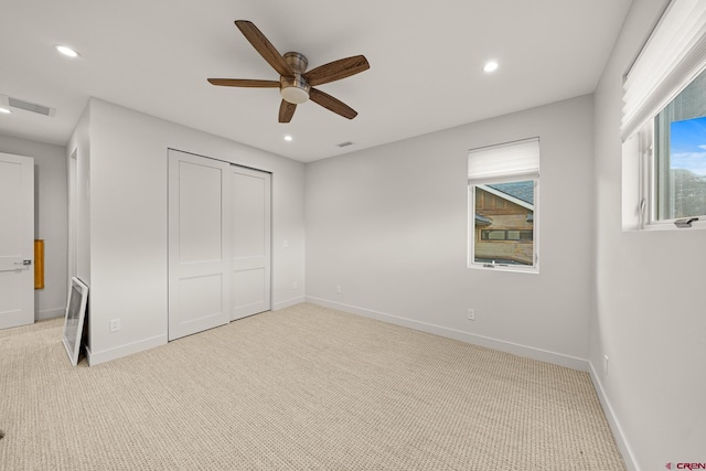 unfurnished bedroom with light carpet, a closet, and ceiling fan