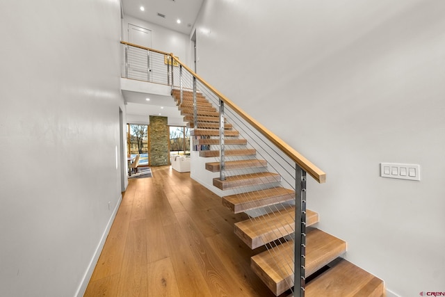 stairs featuring hardwood / wood-style floors and a towering ceiling