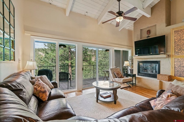 living room featuring a high end fireplace, beam ceiling, light hardwood / wood-style floors, and ceiling fan