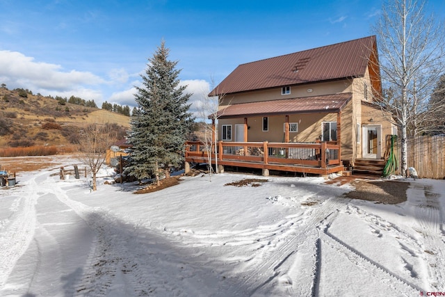 snow covered rear of property featuring a deck