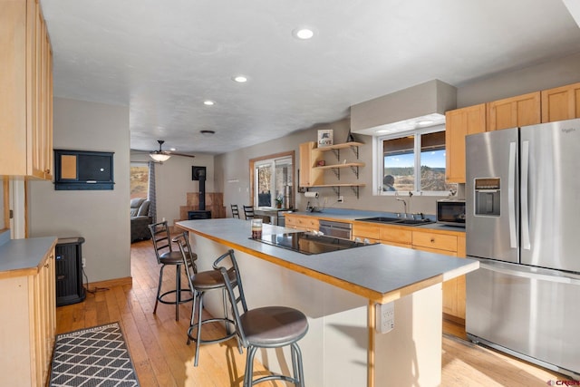 kitchen featuring a center island, a wood stove, stainless steel refrigerator with ice dispenser, and a breakfast bar area