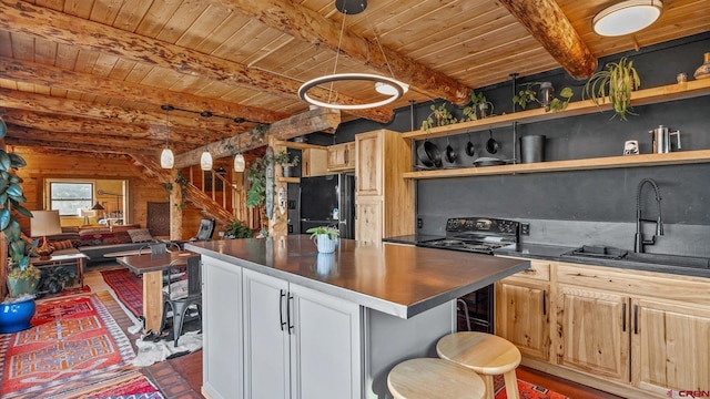 kitchen featuring black refrigerator, a kitchen bar, a center island, and beam ceiling