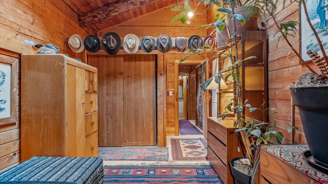 bedroom with vaulted ceiling with beams, wooden walls, and wood ceiling