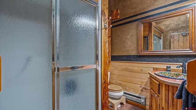 bathroom with vanity, toilet, a shower with door, and wooden walls