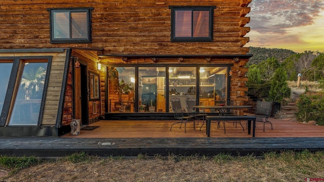 back house at dusk featuring a wooden deck